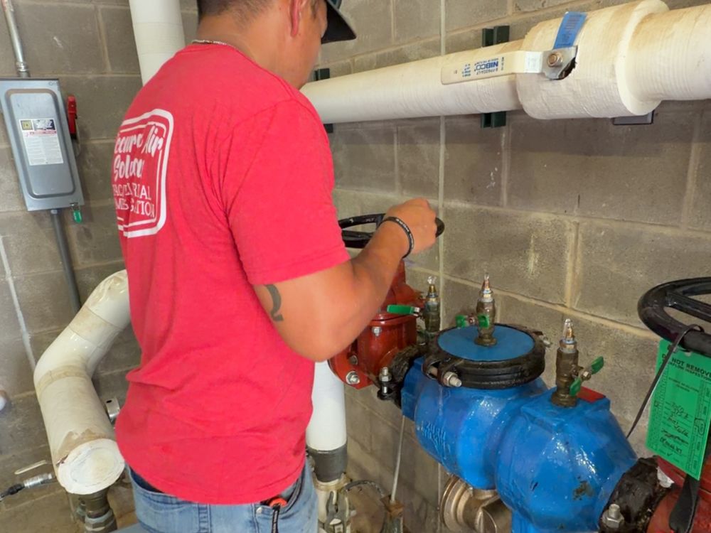 Double R Plumbing technician testing a commercial backflow prevention assembly